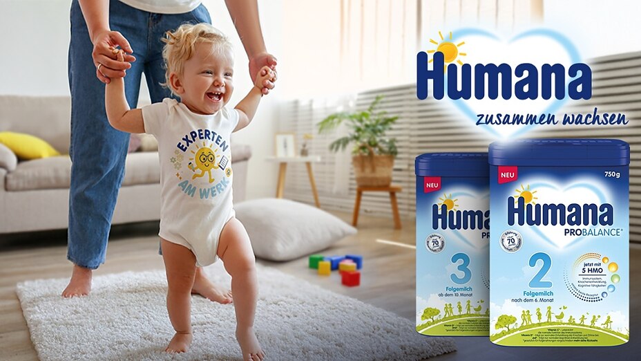 Kleinkind macht erste Gehversuche, begleitet von einer erwachsenen Person.