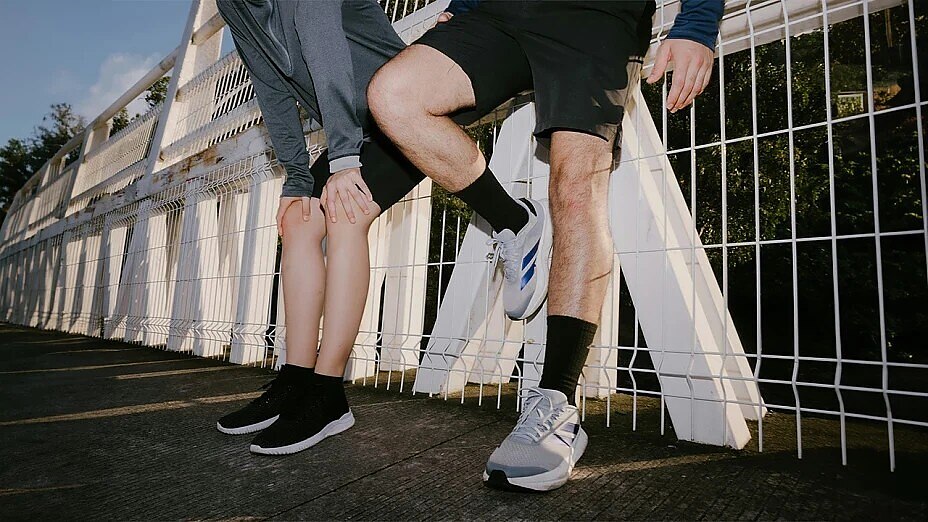 Zwei Läufer lehnen an weißem Zaun