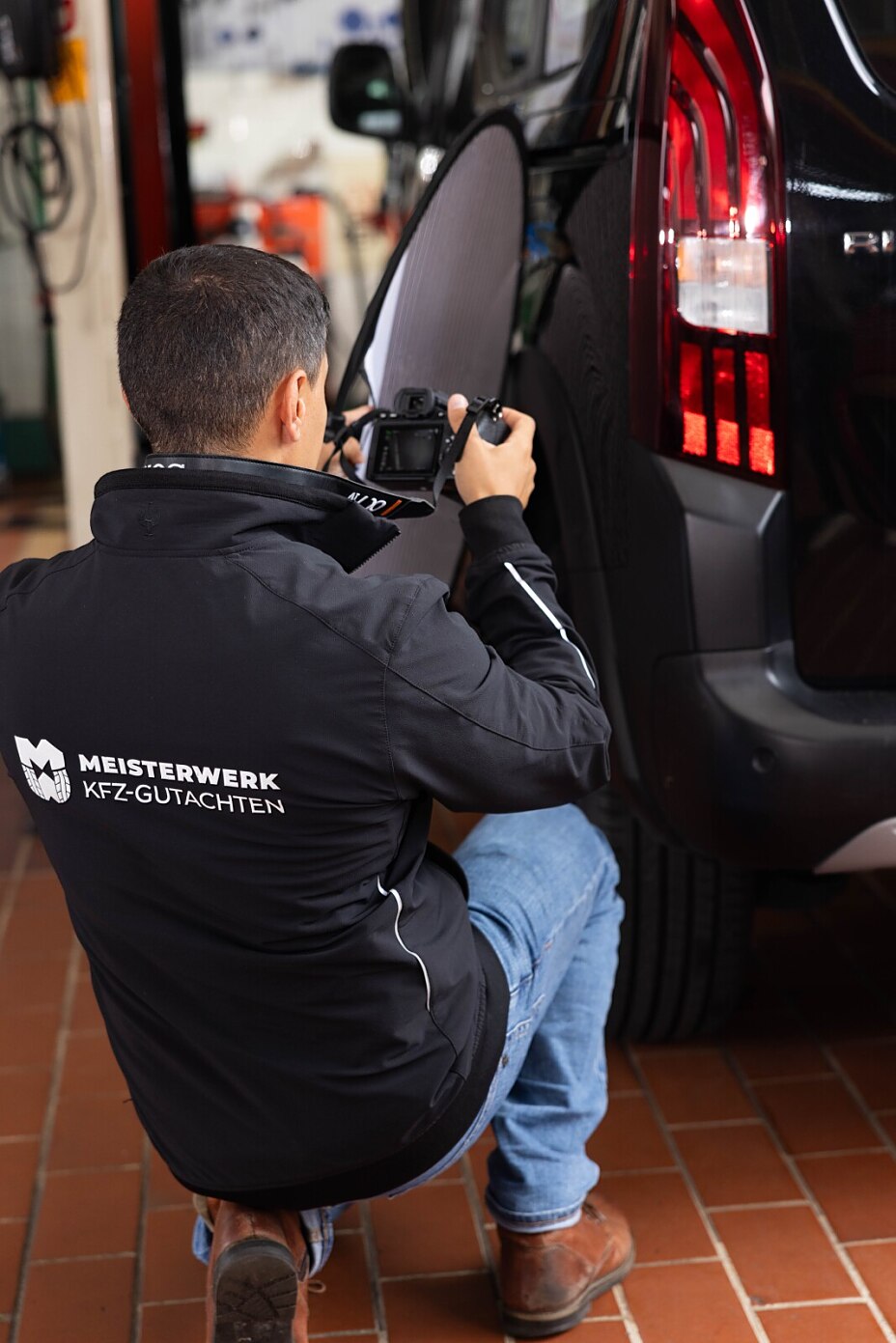 Kfz Gutachter dokumentiert Dellen an einem Fahrzeug mit Reflektorsegel