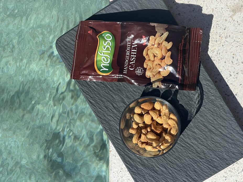 Nefisso Cashews und eine Schale Cashewnüsse auf einer dunklen Platte am Pool